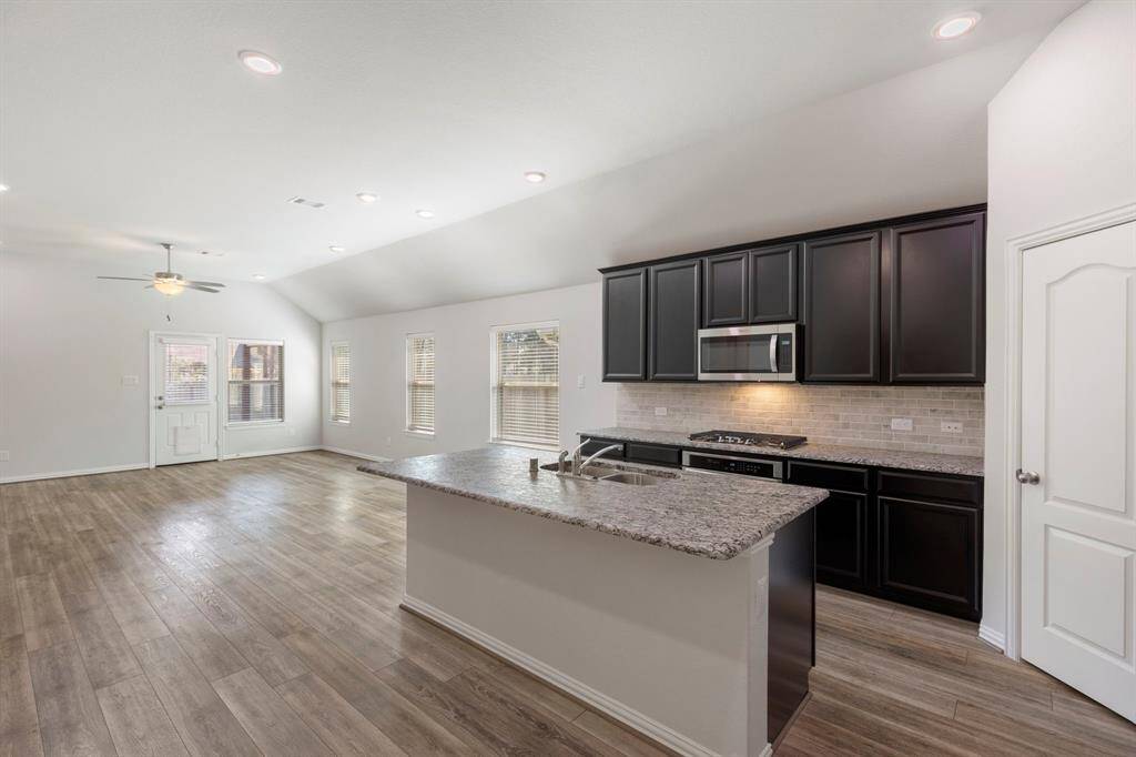 The main living area is open and spacious. It features high ceilings, recessed lighting, ceiling fans, and beautiful island kitchen featuring leather textured finished granite.