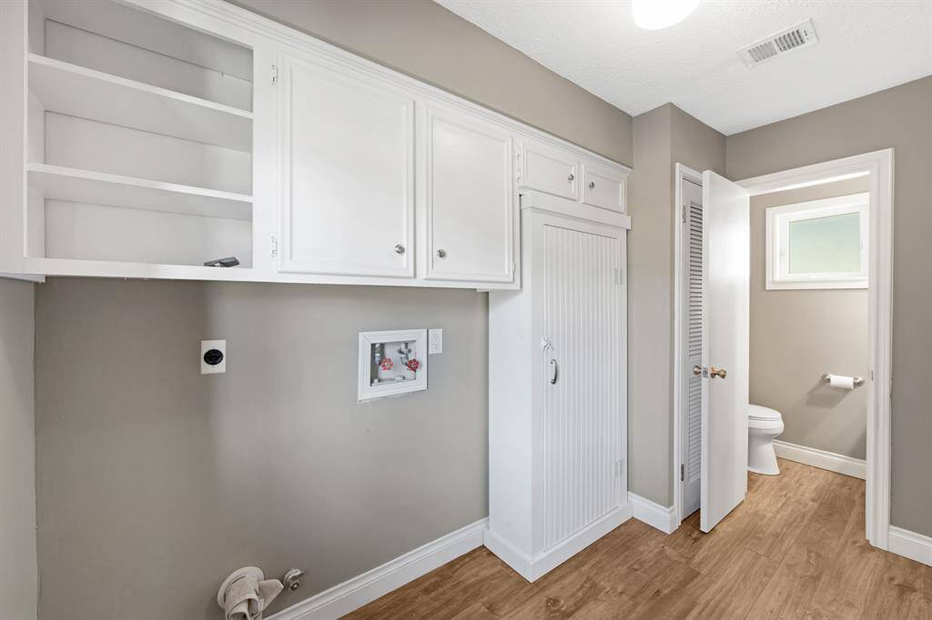 The laundry room is both functional and spacious, featuring additional built-in cabinetry for ample storage. Conveniently located nearby is a half bathroom, offering easy access and added comfort for residents and guests alike.