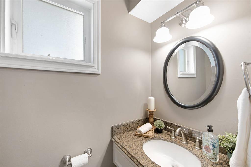 The half bathroom is beautifully appointed with a sleek granite countertop and a framed mirror, adding a touch of elegance to this convenient space. It's a stylish and functional feature for guests and everyday use.