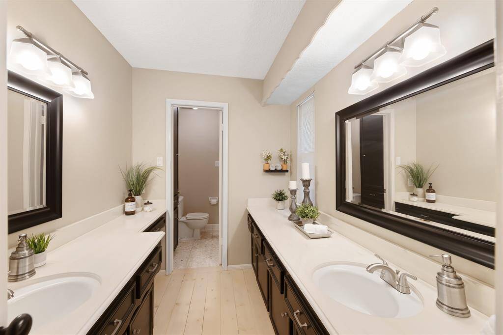 The primary ensuite is a luxurious space with elegant tile flooring, two large vanities, and framed mirrors that add a touch of sophistication. It also features a convenient tub/shower combo, offering both comfort and style for your daily routine.