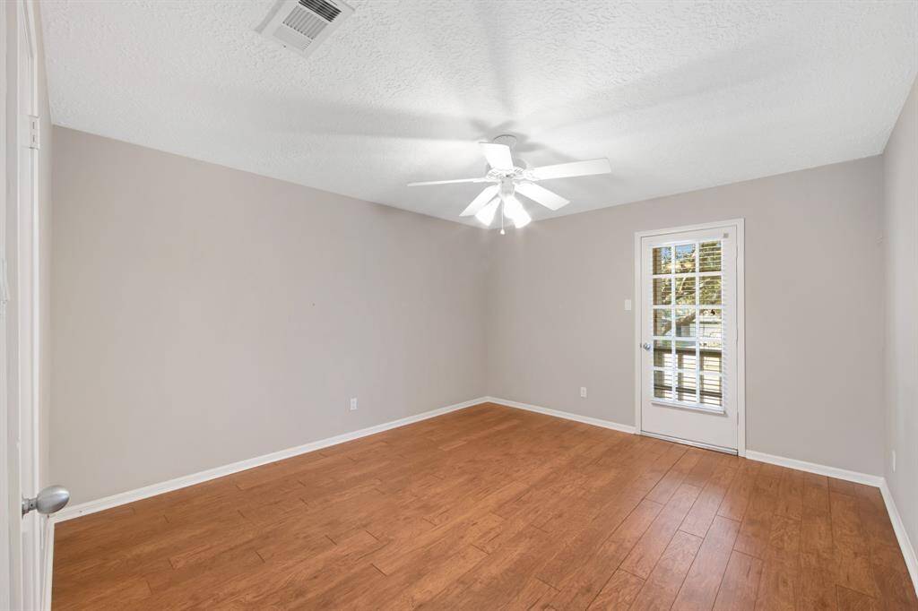 The secondary bedroom features stylish wood-like tile flooring and offers direct access to the balcony, providing a peaceful retreat with lovely outdoor views.
