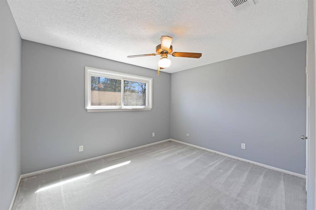 Secondary bedroom with plush carpeting and ceiling fan.