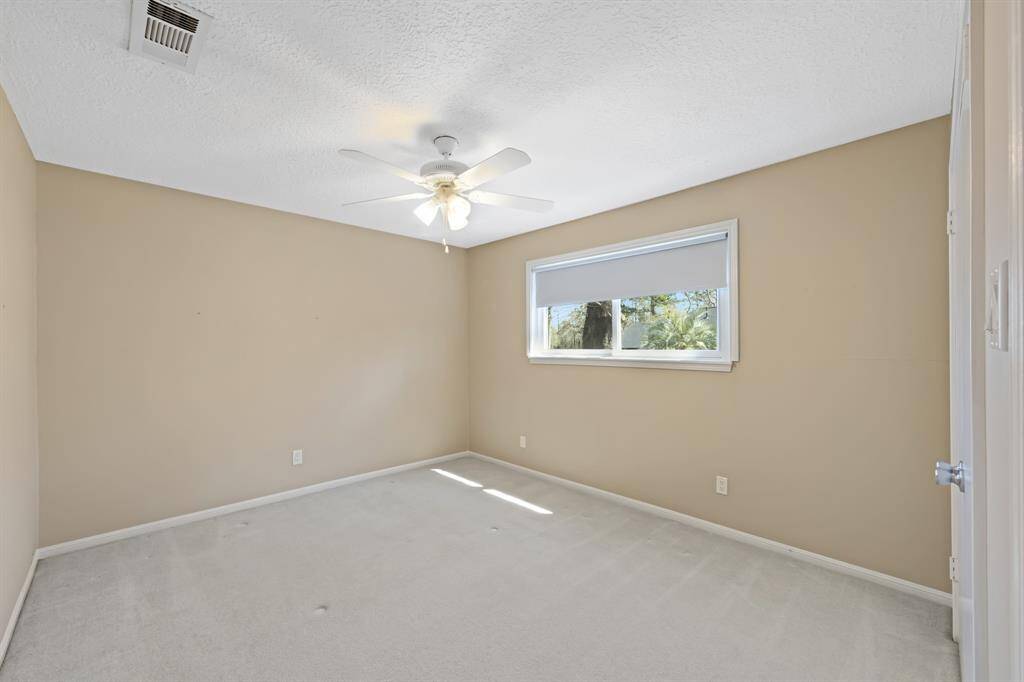 Secondary bedroom with plush carpeting, ceiling fan and pull down shade.