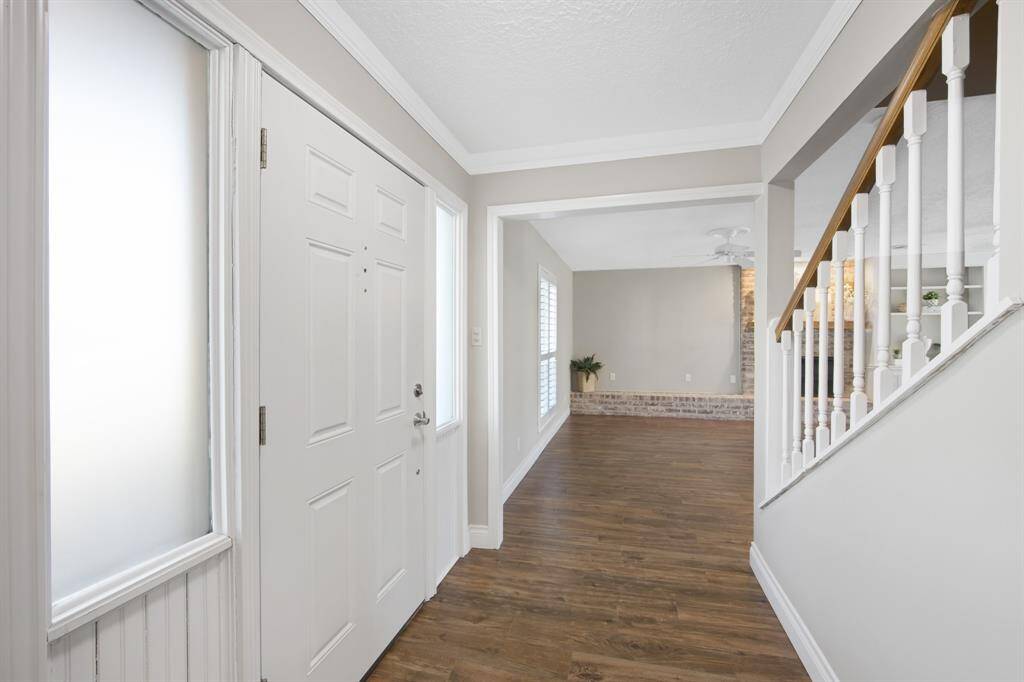 The downstairs area features elegant wood-like tile flooring, creating a warm and inviting atmosphere throughout. The entryway is enhanced with beautiful crown molding, adding a touch of sophistication and charm as you step into this stunning home.