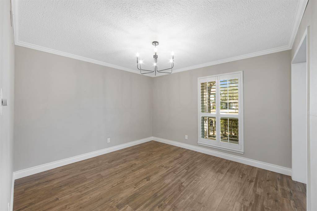 The formal dining room is a refined space, featuring exquisite crown molding that adds an air of elegance. Plantation shutters frame the windows, allowing for controlled natural light and enhancing the room's sophisticated appeal.