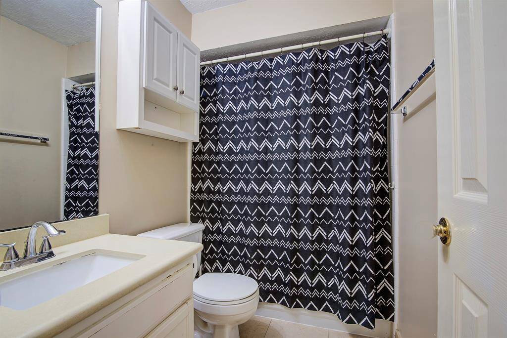 This guest bathroom features a clean, modern design with a white vanity and sink,  and a wall-mounted cabinet for storage. Neutral walls and a tiled floor complete the space.