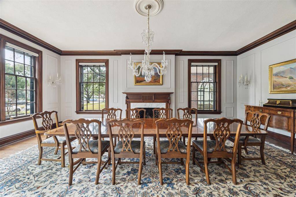 Highlighted by a stunning crystal chandelier, elegant wall sconces, and a wood-burning fireplace with a marble surround, this generously sized dining room is framed by large windows that fill the space with beautiful natural light.