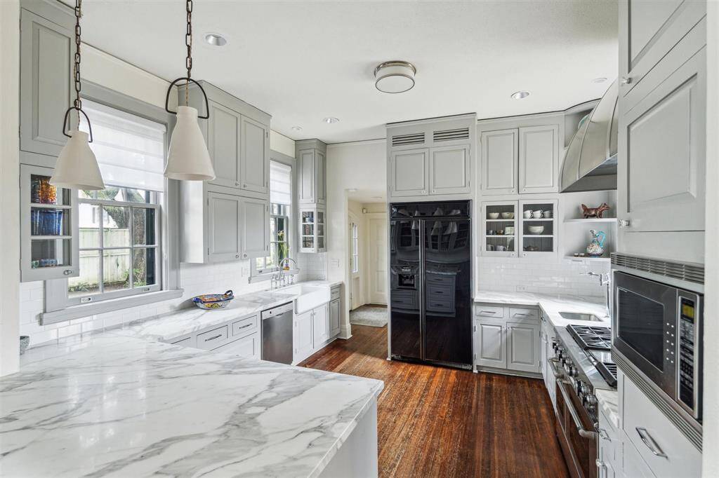 This stylish kitchen features chic marble counters, warm hardwood floors, and abundant natural light streaming through large windows.