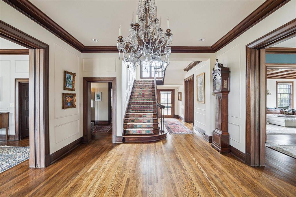 A sophisticated entryway welcomes you into the home's timeless charm with a grand crystal chandelier serving as a striking centerpiece. The spacious and elegant foyer showcases gleaming hardwood floors and a grand staircase accented by framed by rich woodwork and thoughtful architectural details and provides direct access to the formal dining and living room.