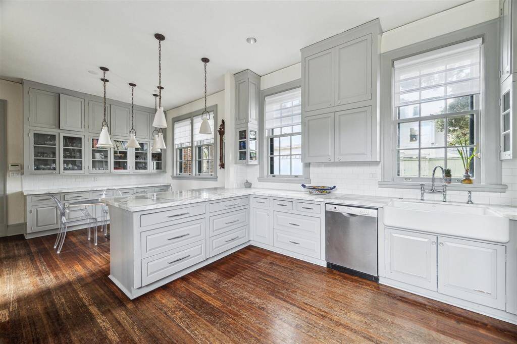 The spacious kitchen features a large farmhouse sink with chrome hardware, elegantly framed by multiple windows that fill the space with natural light.