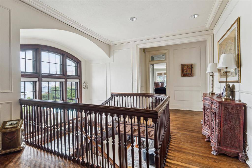 Ascending the elegant stairway, we come to the second-floor landing that features rich hardwood floors, intricate wood banisters, and stunning arched windows that flood the space with natural light. The timeless design and detailed millwork create a warm and sophisticated ambiance.