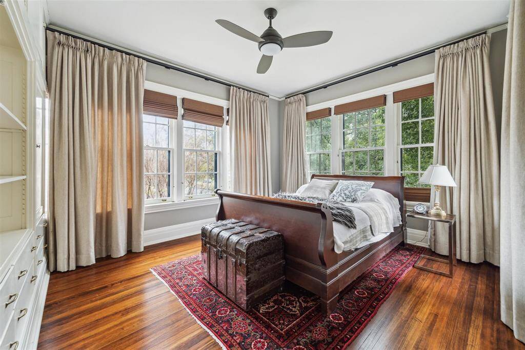 Tucked away for added privacy, bedroom 4 exudes warmth and charm with its rich hardwood floors, classic built-ins, and large windows framing serene treetop views. The neutral palette and timeless design make it an inviting and tranquil retreat.