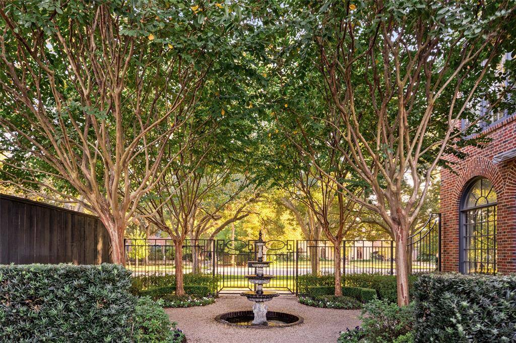 Just off the sun room, an enchanting courtyard is a private oasis, framed by elegant crepe myrtle trees and manicured hedges. A classic tiered fountain serves as the centerpiece, creating a tranquil ambiance perfect for relaxation or entertaining.