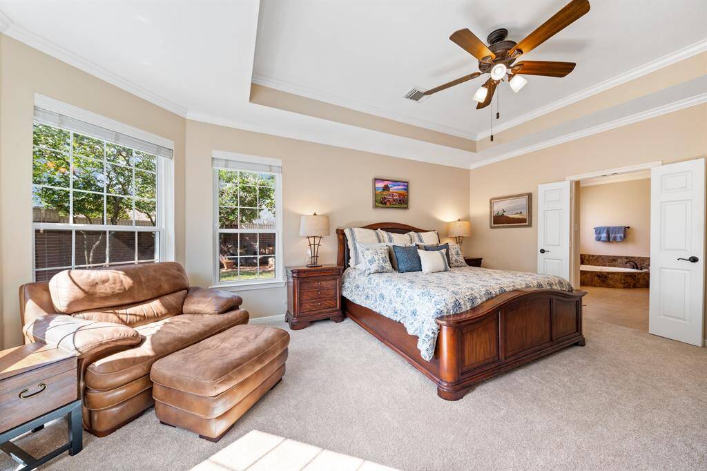 The primary bedroom is spacious with views of the back yard. The open double doors lead to the elegant ensuite.The tray ceiling is a lovely design feature, and the carpet is less than a month old.