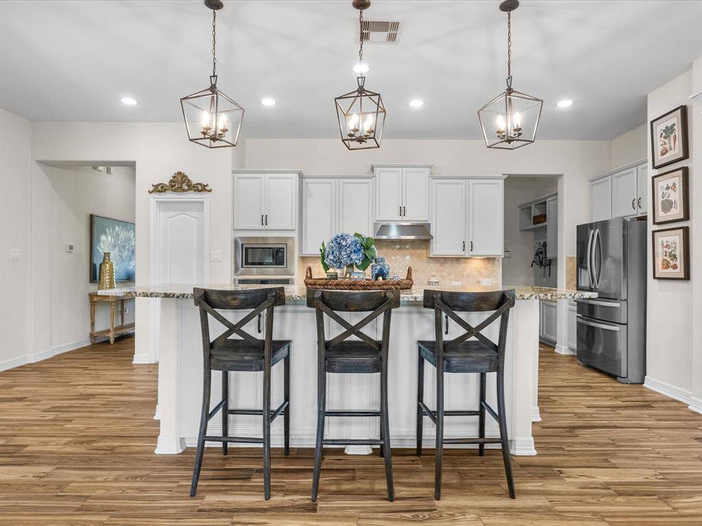 The kitchen offers a granite island and generous storage. Its open layout enhances connectivity with adjacent living spaces.