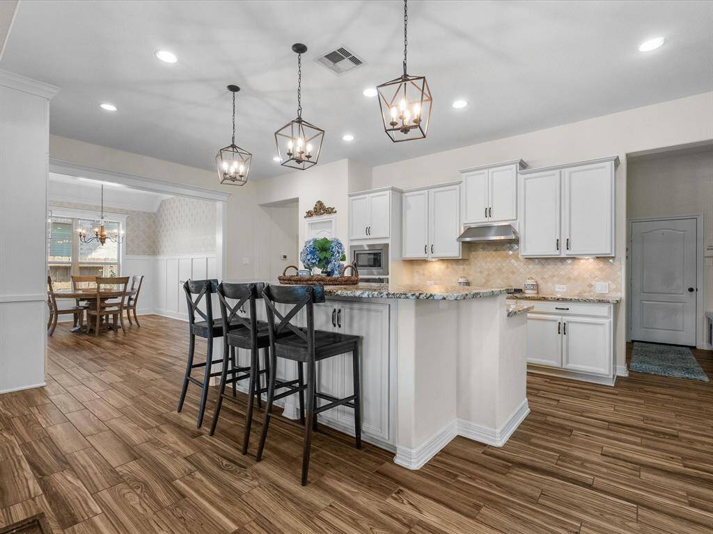 The kitchen features a granite countertop island and modern cabinetry. The open layout connects to the breakfast area, providing a seamless flow for daily living.