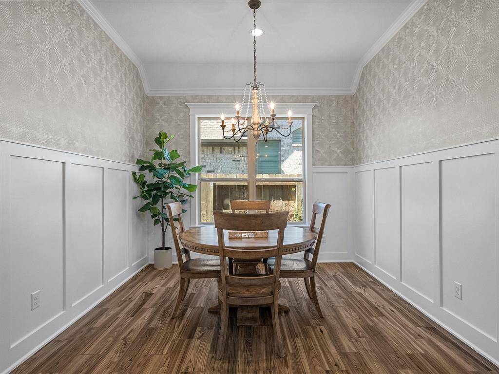 The breakfast room features updated board and batten trim molding and modern wallpaper, creating a bright and inviting space. The room is enhanced by natural light.