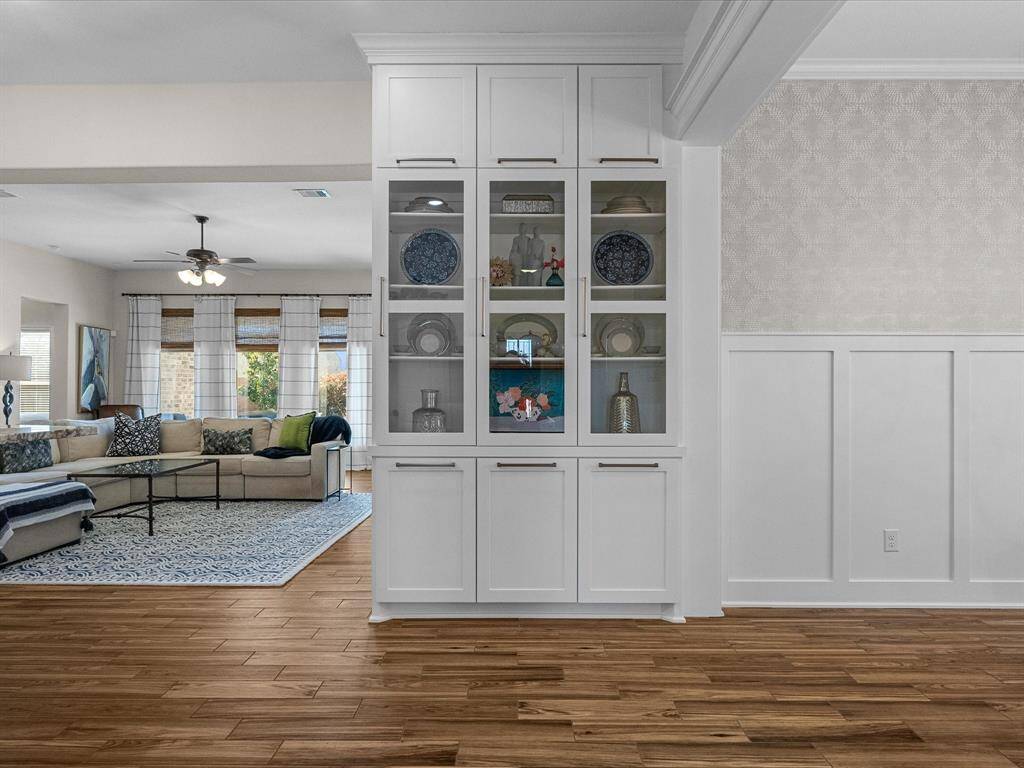 Custom built-in china cabinet, offering elegant display and storage.  Adjacent, upgraded board and batten molding, and patterned wallpaper accent this elegant home, creating a refined and cohesive living space.