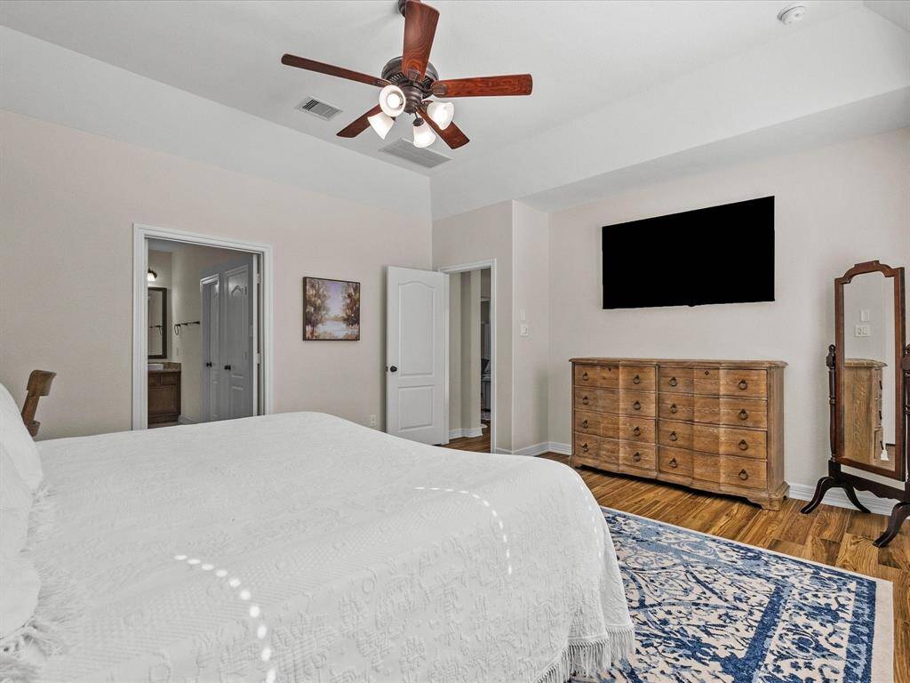 Primary bedroom includes wood look tile and a spacious layout. The room provides a private and comfortable setting.