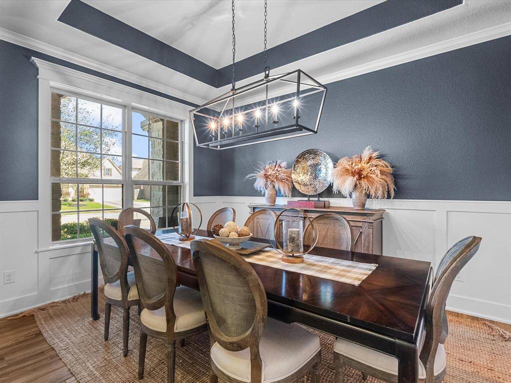 The dining room features updated wainscoting and tray ceiling, and beautiful trim creating a sophisticated ambiance.  The room is filled with natural light, enhancing its elegant design.