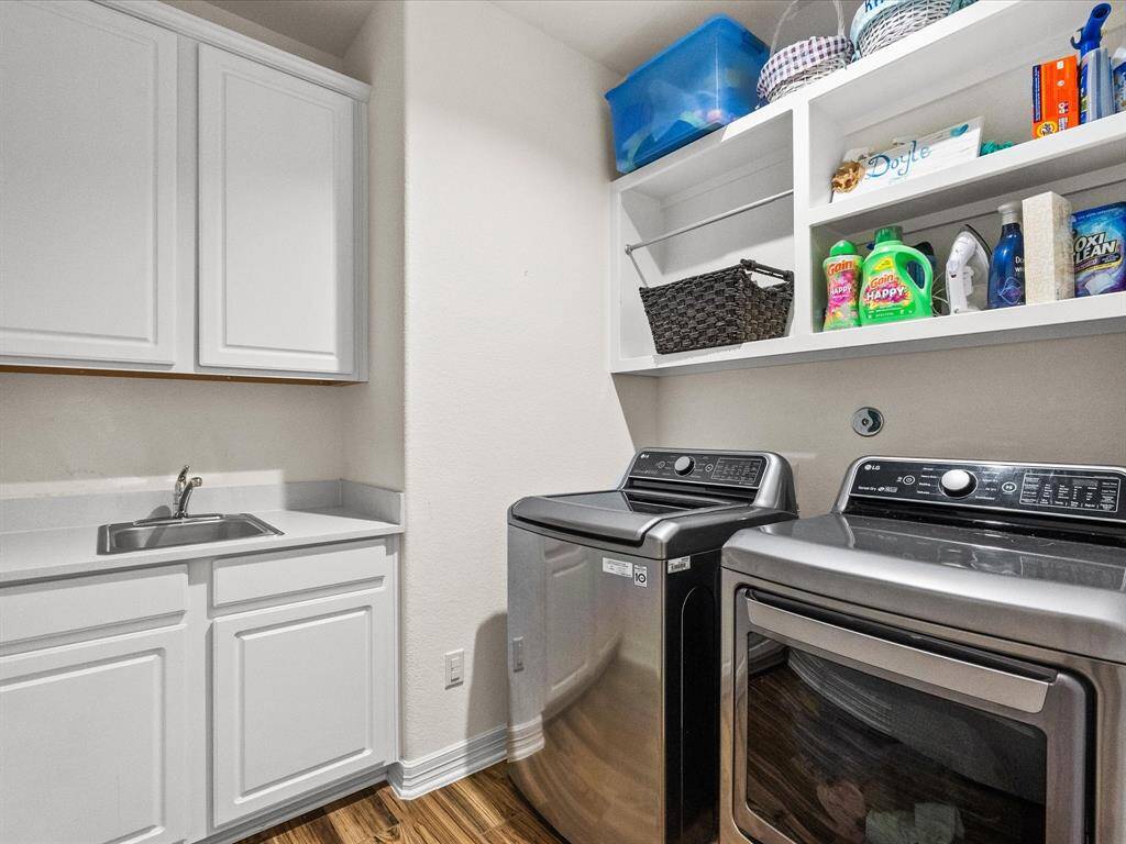 The utility room features built-in shelving and cabinetry, providing ample storage, plenty of space and even a sink for added convenience.