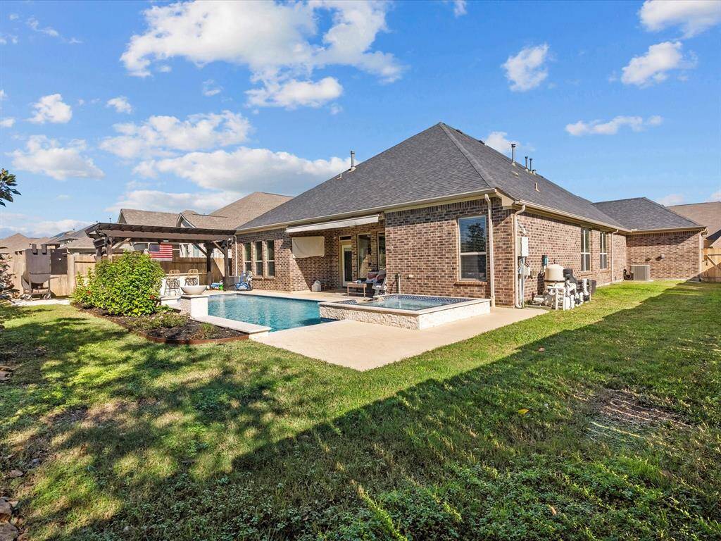 The backyard features a swimming pool and hot tub, complemented by a covered outdoor kitchen.