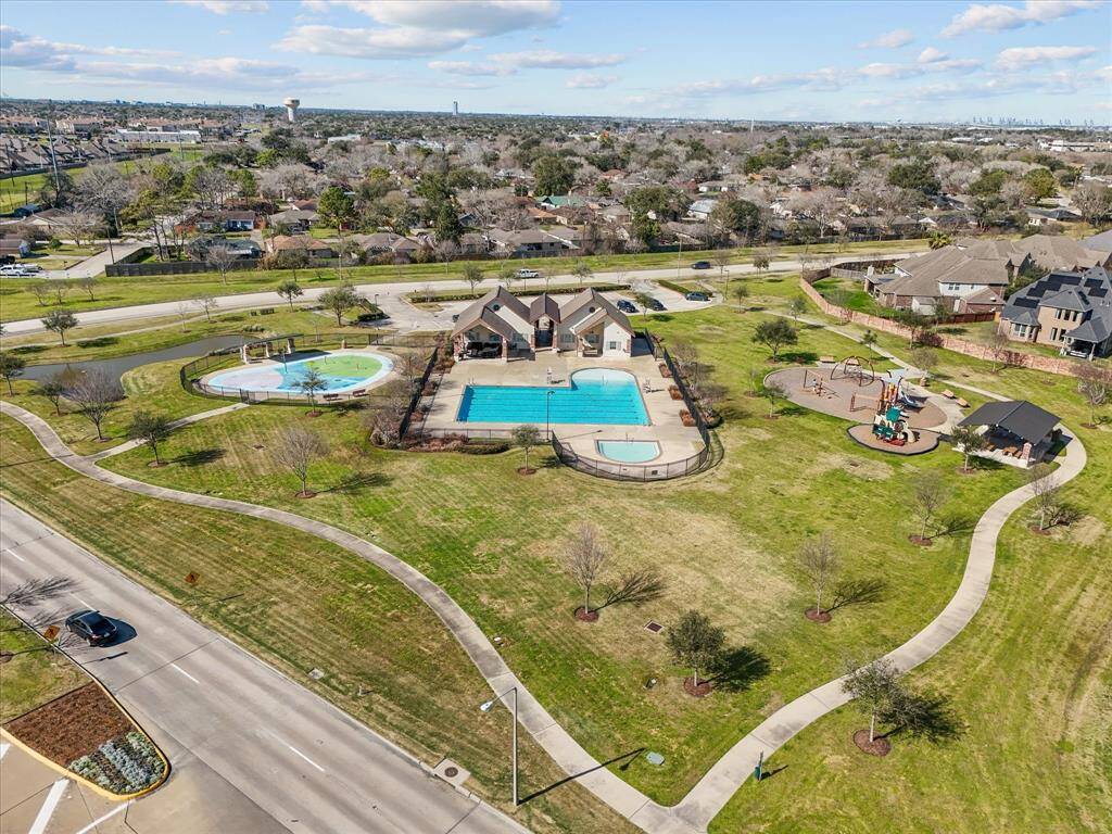 The community recreation area, showcasing a The The community swimming pool, a children's playground, and paved walking paths. The surrounding green space and mature trees offer a pleasant outdoor environment.