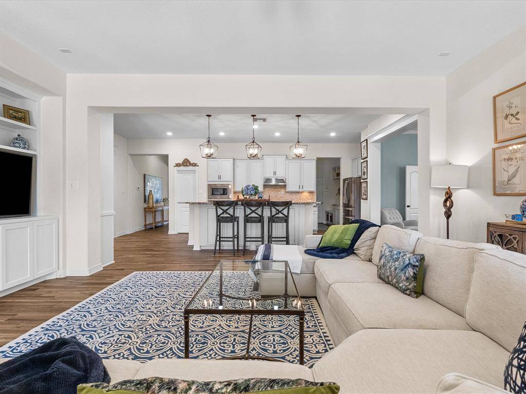 The living room’s open design connects to the kitchen, creating a unified living space. The area is well-suited for both relaxing and entertaining.