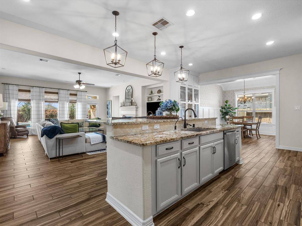 The kitchen features a granite countertop island, modern cabinetry, and stainless steel appliances. The open layout seamlessly connects to the living and breakfast rooms, creating an ideal space for entertaining.