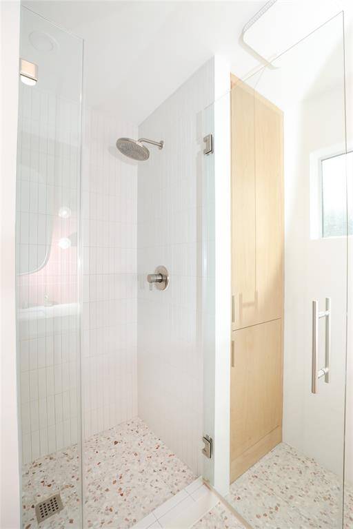 Second bathroom has a frameless glass shower and linen closet beautifully designed to fit with this modern home.