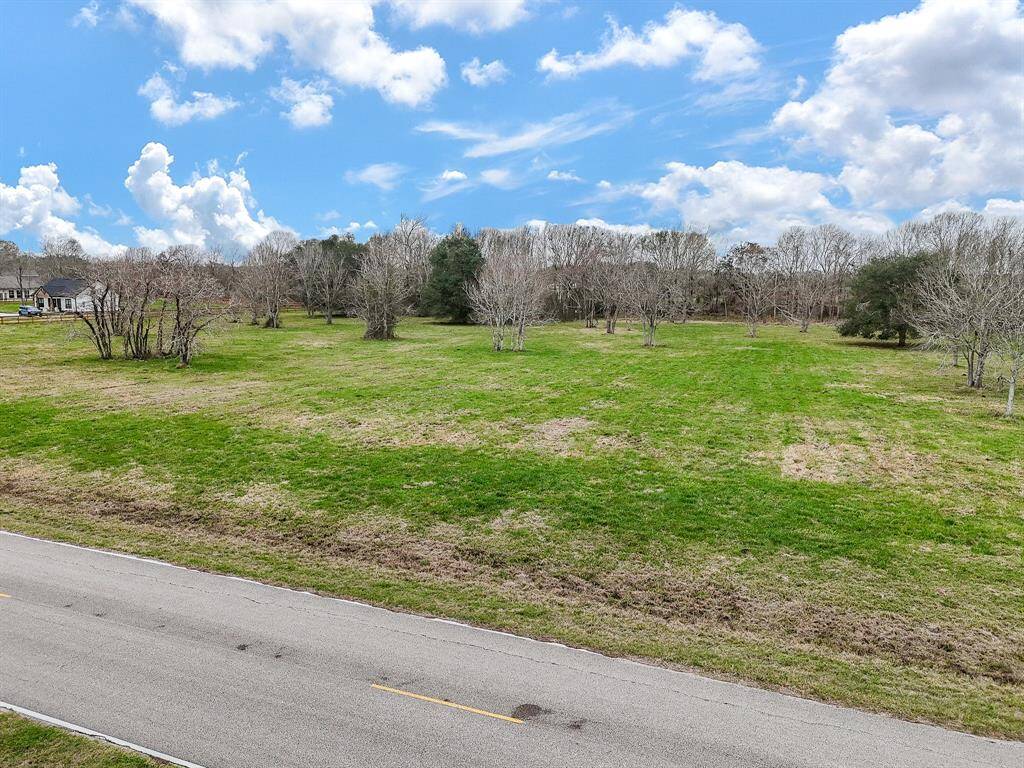 Expansive, grassy lot with scattered trees, ideal for building a home. Quiet road access and serene, open views under a bright blue sky. Great potential for landscaping or outdoor activities.