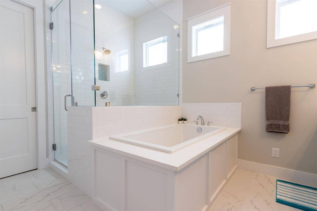 The primary ensuite bathroom is a spa like retreat with modern features, including an open shower with glass enclosure, a separate soaking tub, dual sinks and a walk-in closet.