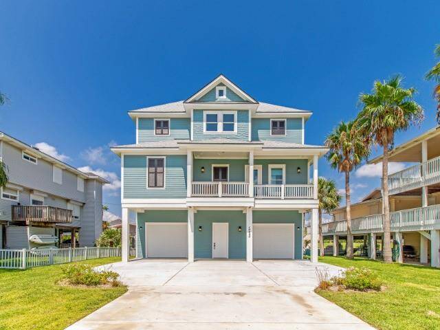 Discover this charming two-story custom-built coastal home with a stunning blue exterior and white trim. Featuring a double garage, inviting front porch, and lush surroundings with palm trees, it exudes a bright, welcoming vibe under a clear blue sky.