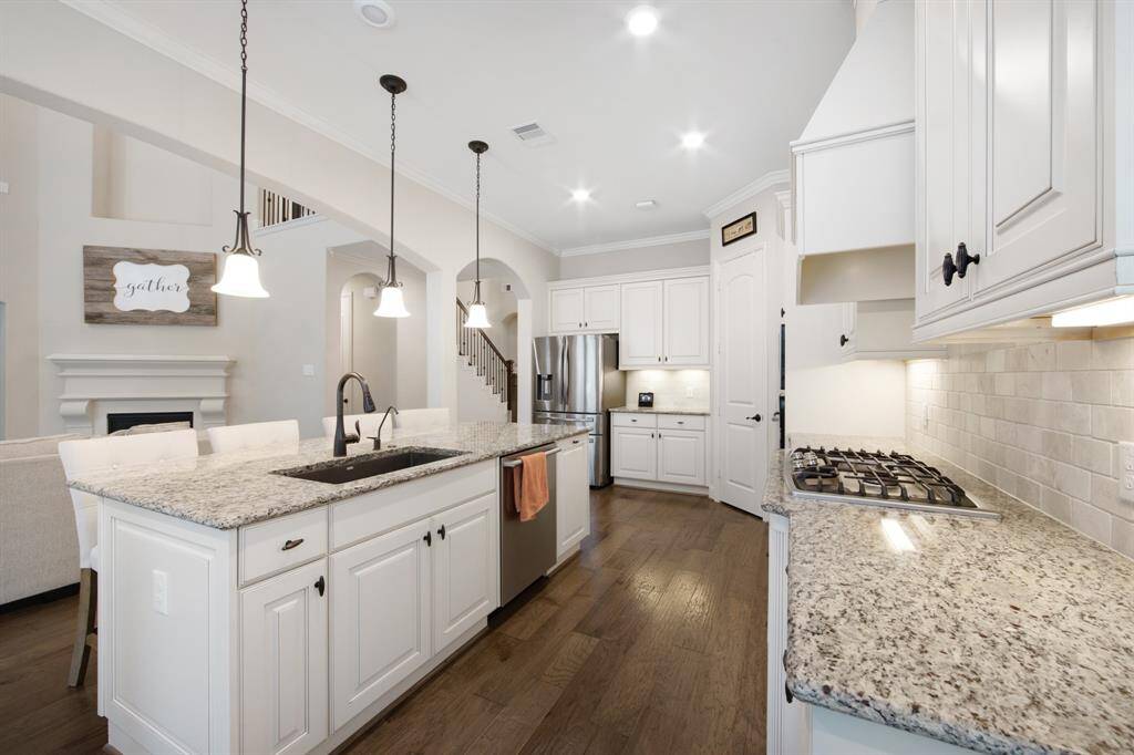 Natural stone back splash, 36" stainless steel gas cooktop with 5 sealed burners, beautiful hardware and canister lights