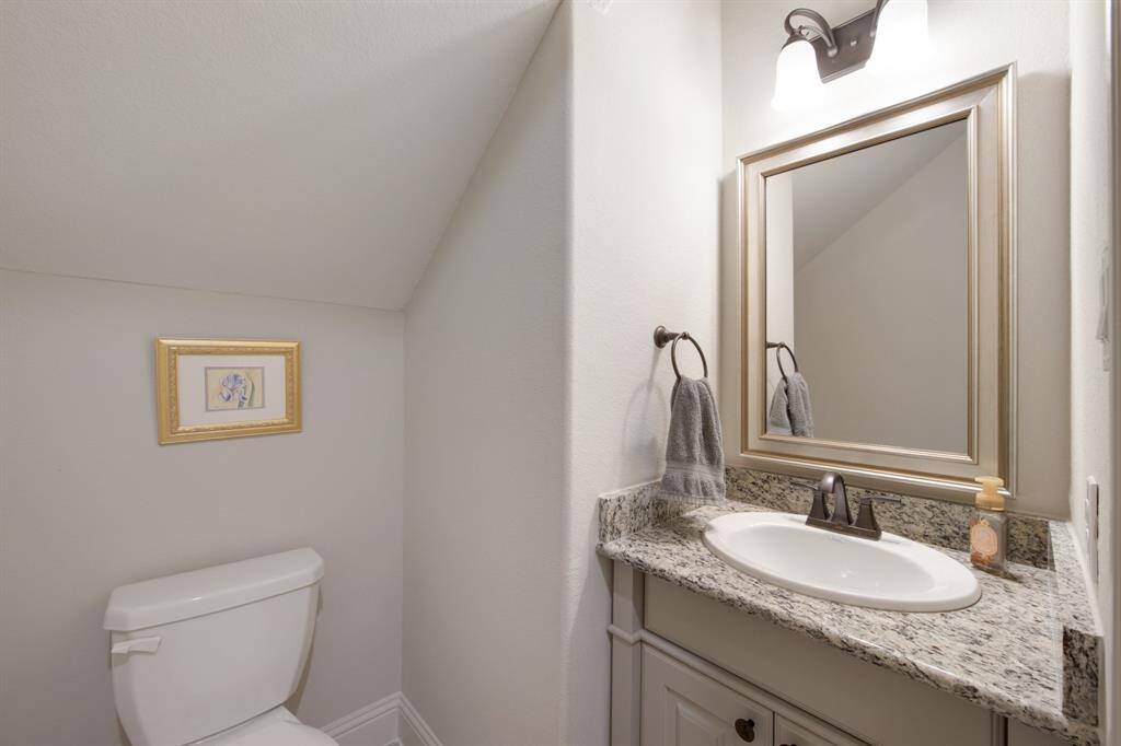Powder room with granite counter cabinet, designer framed mirror, designer tile flooring and elongated toilet