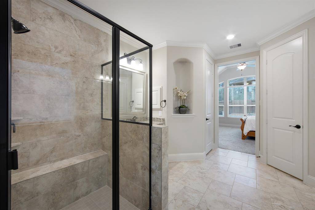 Designer tile shower with metal frame and glass walls, bench and  mesh tile floor. Notice the art niche and the private water closet.