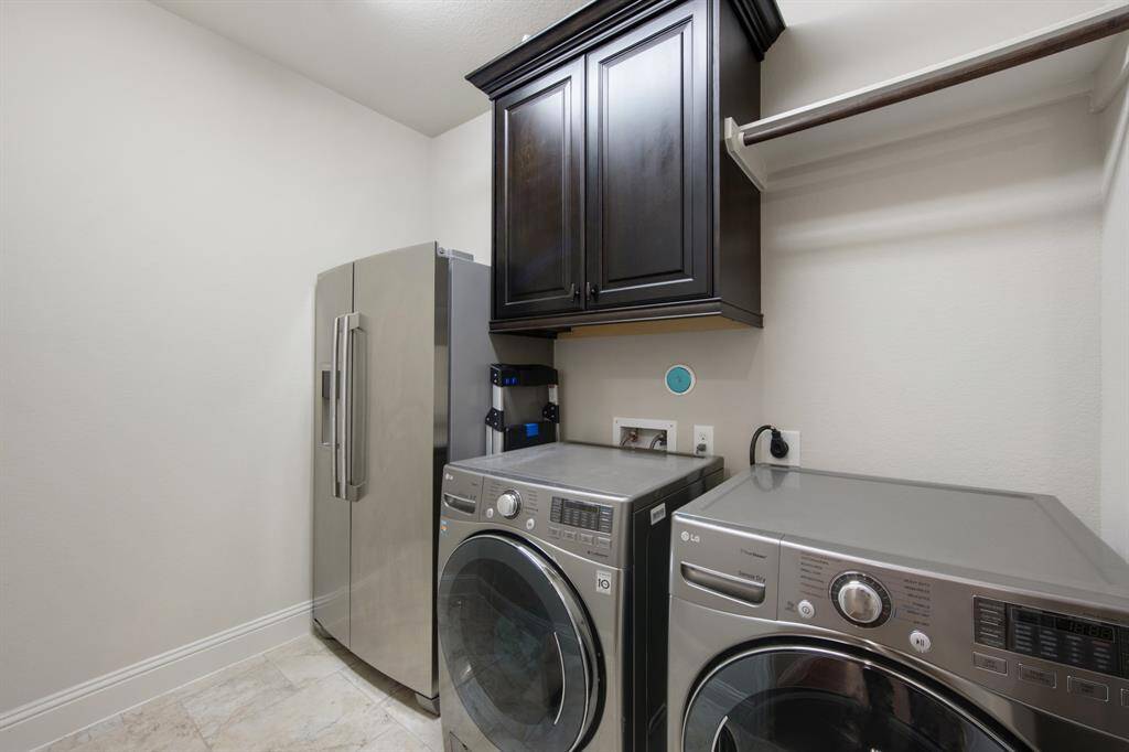 Laundry room with designer tile flooring, overhead cabinet and rod.  Dryer with electric and gas hook-ups. Washer & Dryer included