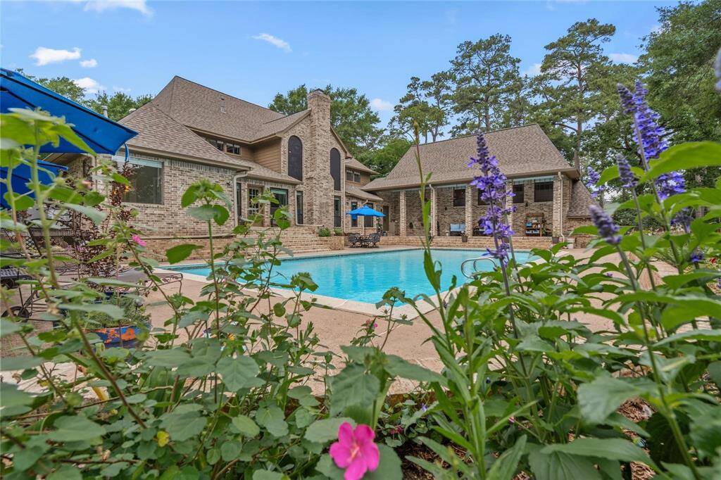 Discover this stunning brick home featuring large windows and a spacious backyard with a pristine pool. Surrounded by lush greenery and vibrant flowers, it offers a serene retreat for relaxation and entertainment.