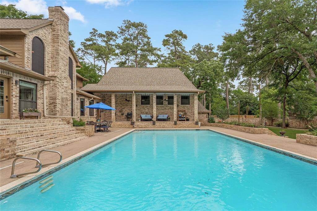 Discover a serene oasis with a spacious backyard featuring a large pool, a charming brick house, and a covered patio. Nestled among mature trees, this private retreat is perfect for relaxation and outdoor entertaining.