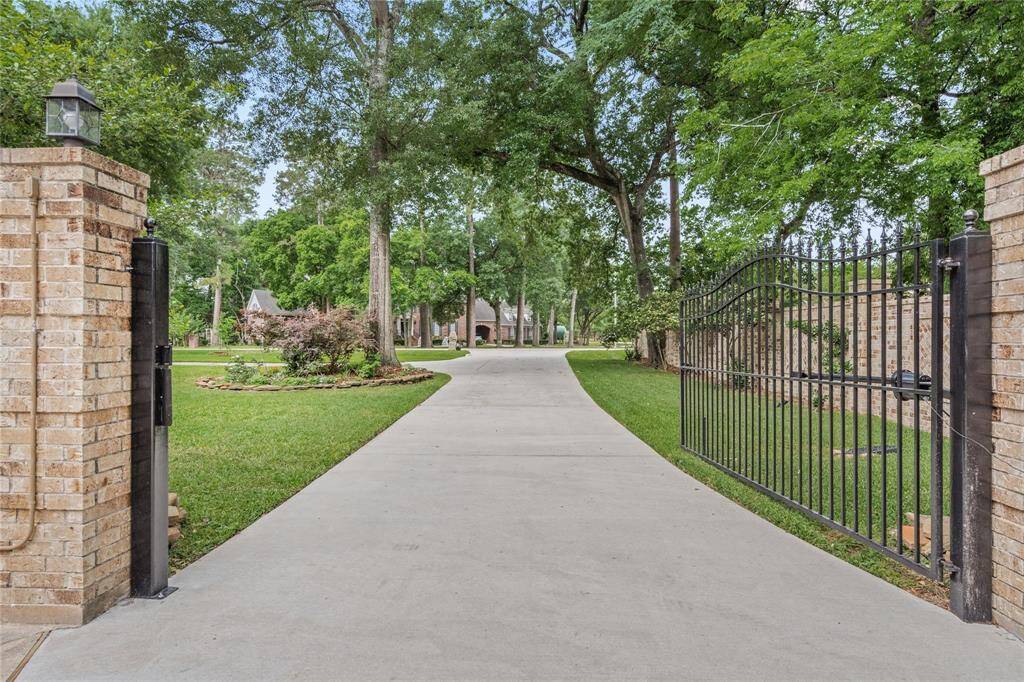 Welcome to this charming home, accessible via a long, paved driveway lined with mature trees. Enter through a stylish brick and wrought-iron gate into a beautifully landscaped, park-like oasis.