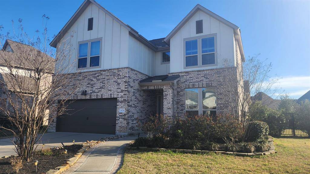 This charming two-story home features a modern brick and siding exterior, a spacious two-car garage, and a well-maintained front yard with mature landscaping.