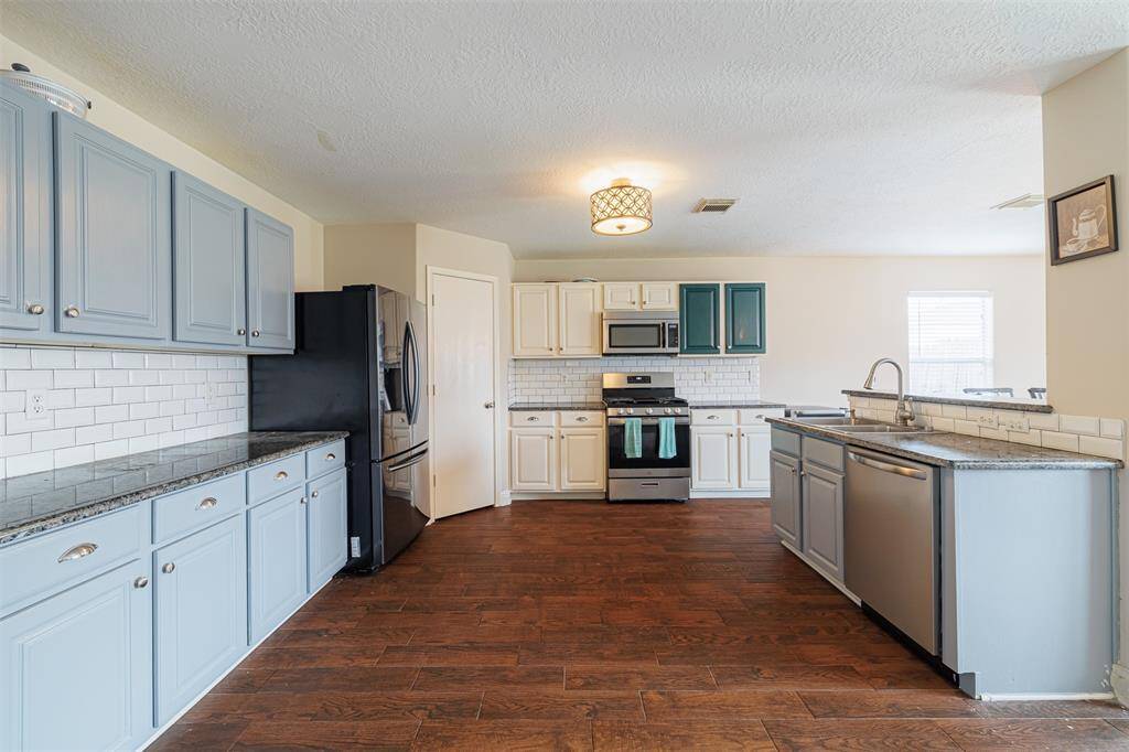 Kitchen features granite counters, lots of cabinets and tile backsplash.