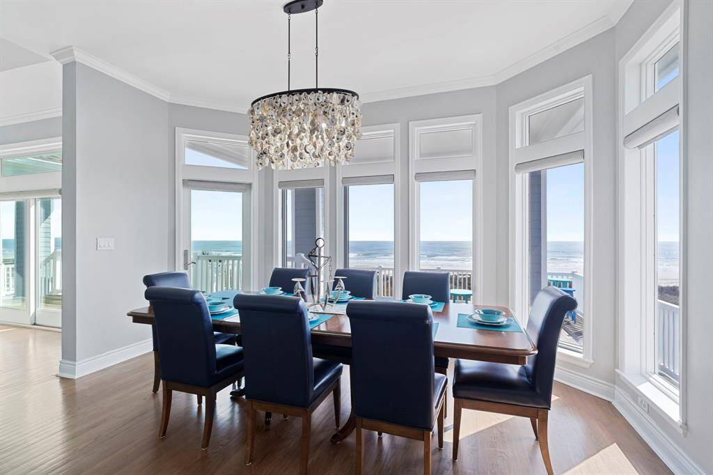 This dining room is bathed in naturallight streaming through expansivewindows and a beautiful chandelier above.