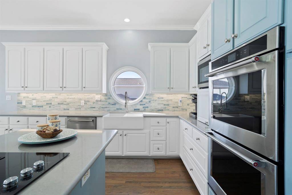 The kitchen features white cabinets, stainless steel appliances, tile backsplash, and a farmhouse sink.