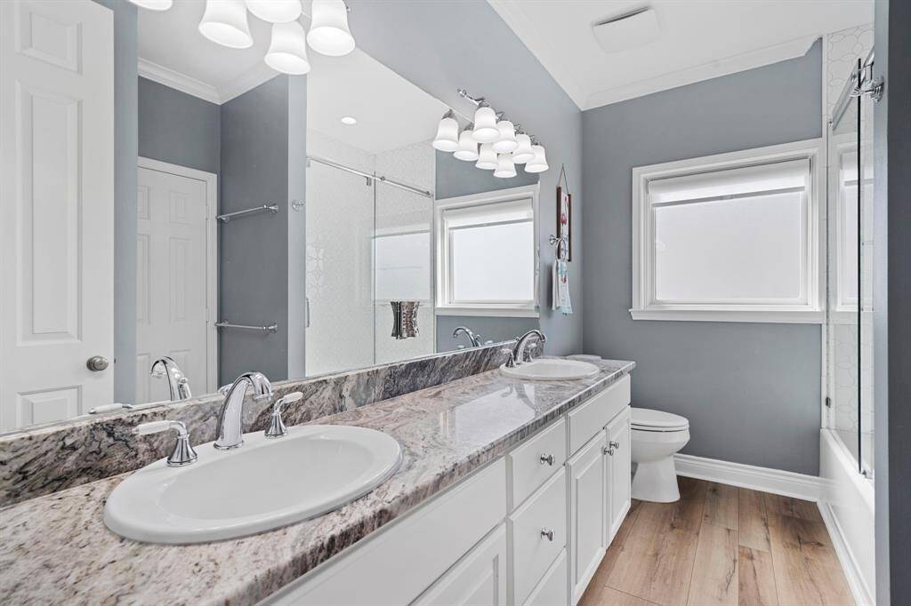 Fourth bathroom features dual sinks, white cabinets, and tub and shower combo with glass door.