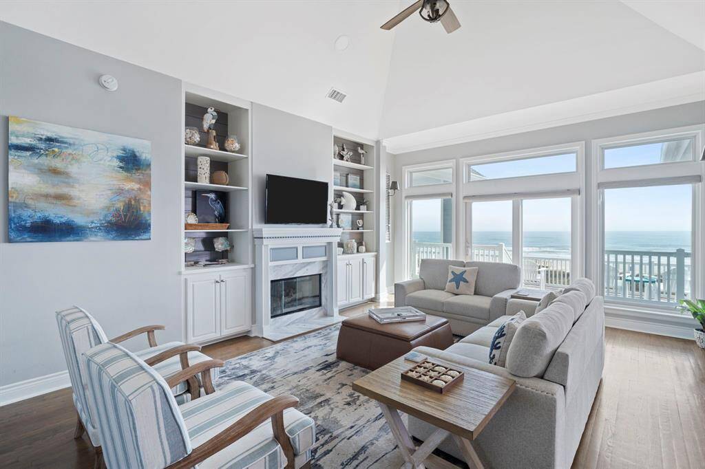 The living room features large windows, high ceilings, built-in shelving, and cozy fireplace.