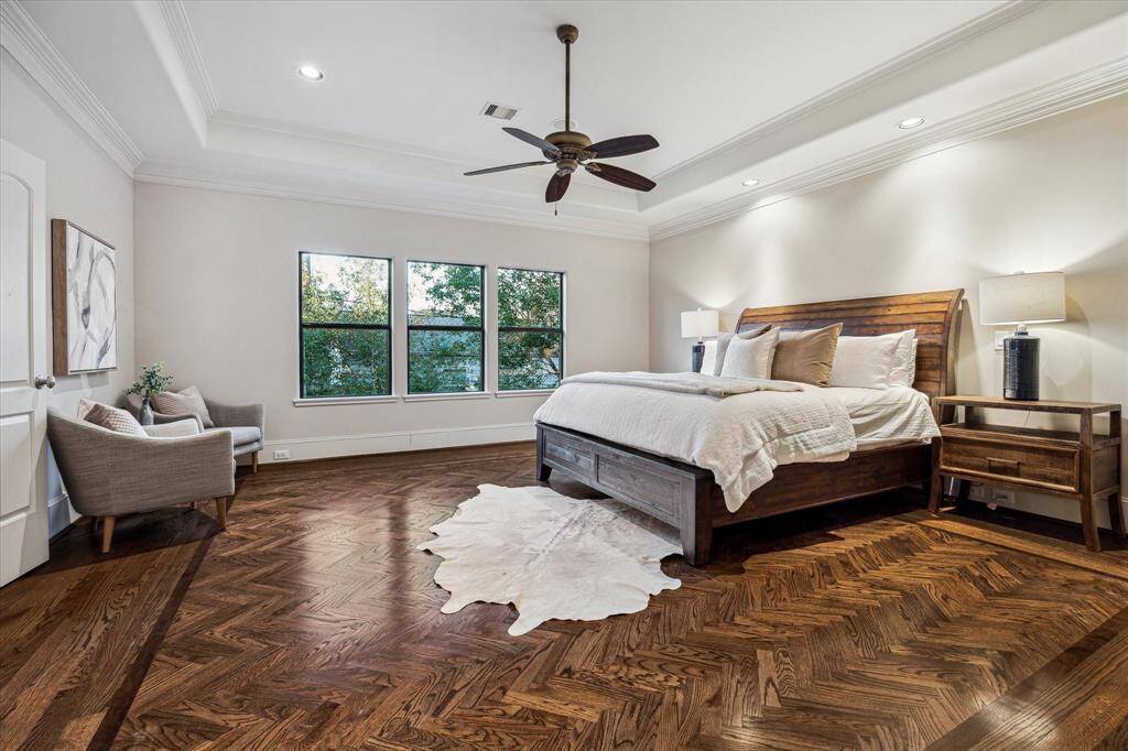 Spacious 2nd floor primary suite with gorgeous wood inlay flooring in a herringbone pattern, tray ceiling, ceiling fan, 3 large windows and recessed lighting.