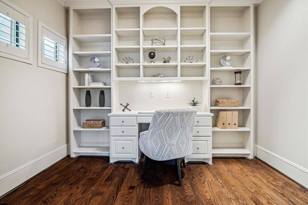 Pocket doors from the primary bedroom open to a home office, complete with a built-in desk and shelving for a functional yet sophisticated workspace.