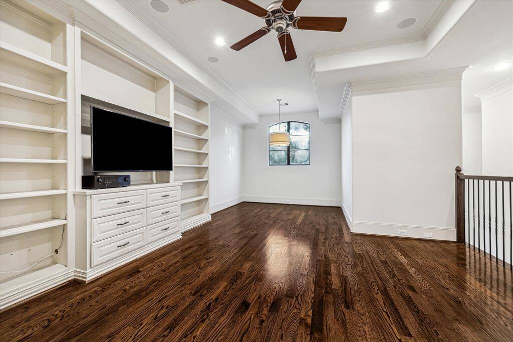 Game room featuring built-ins, hardwood floors, surround sound speakers, and a nook ideal for a game table, creating the perfect space for entertainment and relaxation.