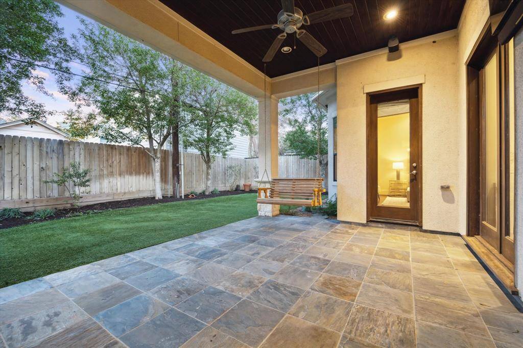 The covered back patio, complete with a ceiling fan, offers the perfect space to unwind and relax year-round.